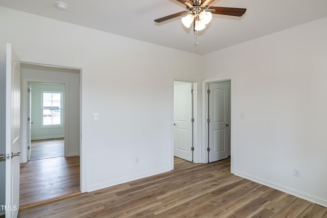 empty room with ceiling fan, wood finished floors, a smoke detector, and baseboards