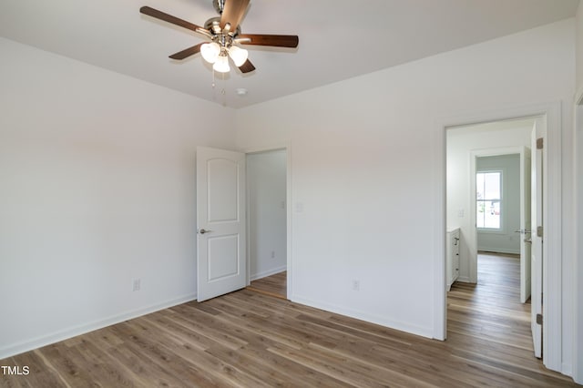 empty room with a ceiling fan, wood finished floors, and baseboards