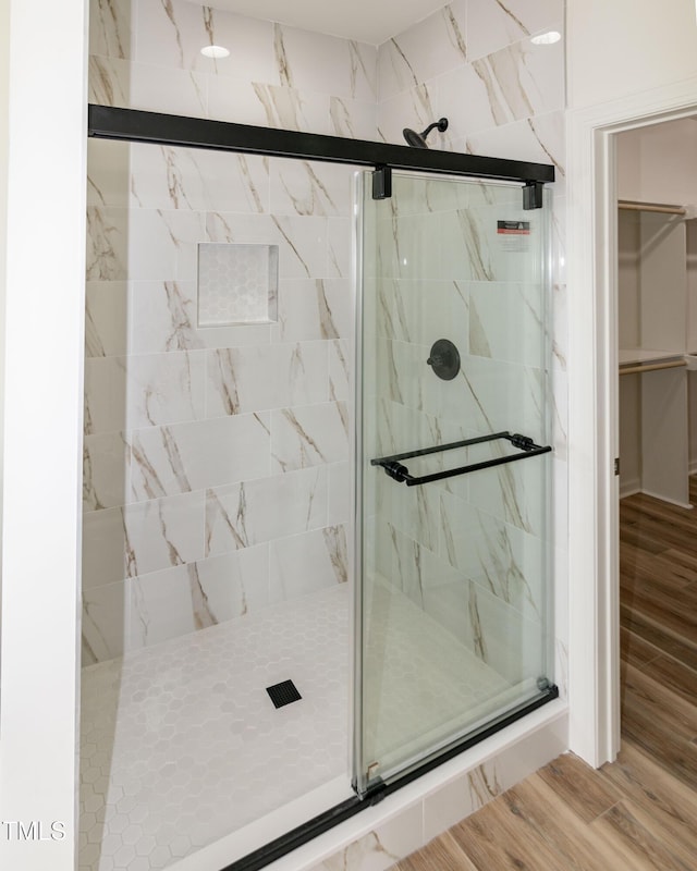 bathroom featuring a marble finish shower and wood finished floors