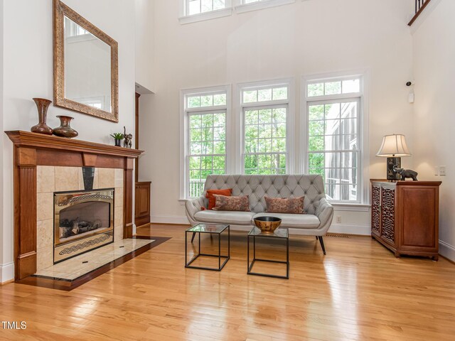 540 Vista Del Lago Ln, Wake Forest, NC 27587 - living room featuring light wood-style floors, baseboards, a tile fireplace, and a towering ceiling