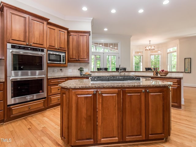 540 Vista Del Lago Ln, Wake Forest, NC 27587 - kitchen with appliances with stainless steel finishes, crown molding, a center island, light wood-style flooring, and a chandelier