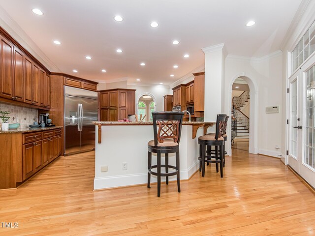 540 Vista Del Lago Ln, Wake Forest, NC 27587 - kitchen with built in refrigerator, a peninsula, crown molding, arched walkways, and a kitchen bar