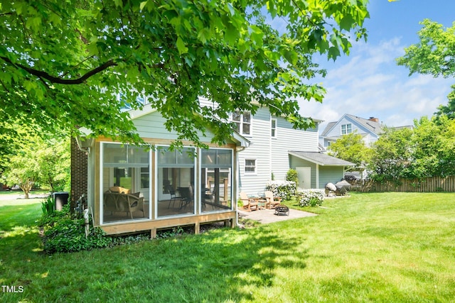 rear view of house with a sunroom, a fire pit, and a patio