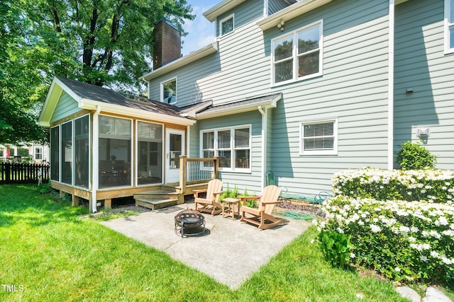 back of house with a sunroom, a fire pit, a chimney, and a patio