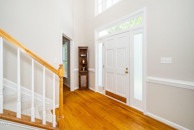 entryway featuring wood finished floors, stairway, and a high ceiling