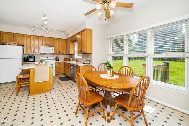 kitchen featuring white appliances, light countertops, a center island, a sink, and a ceiling fan