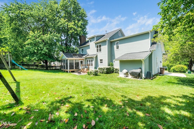 rear view of property with a sunroom, a playground, and a chimney