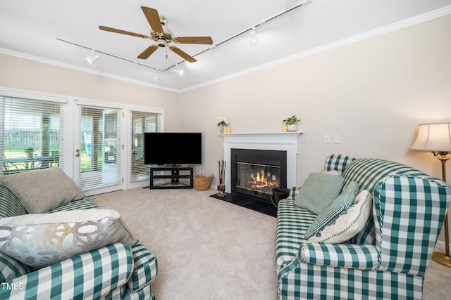 living area featuring track lighting, carpet, crown molding, a ceiling fan, and a fireplace with flush hearth