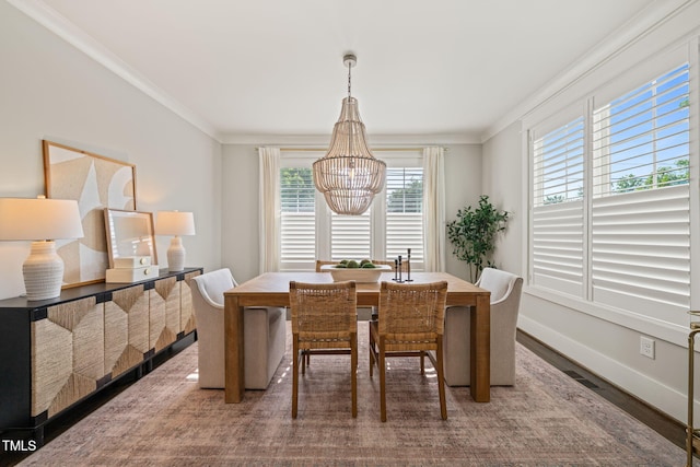 dining space featuring baseboards, an inviting chandelier, ornamental molding, and wood finished floors