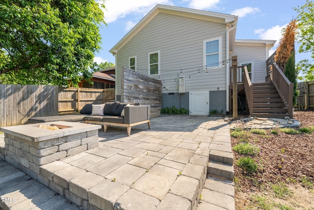 back of house featuring a fenced backyard, an outdoor living space with a fire pit, a patio area, and stairway