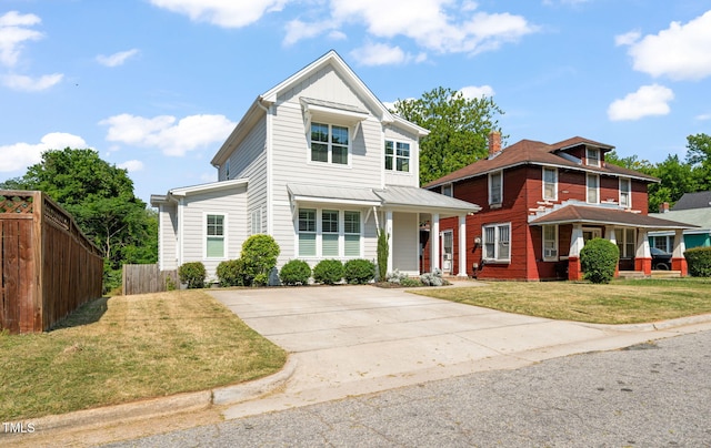 traditional-style house with covered porch, fence, driveway, and a front lawn