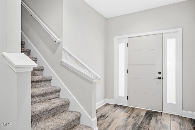 entrance foyer featuring baseboards, stairs, and wood finished floors