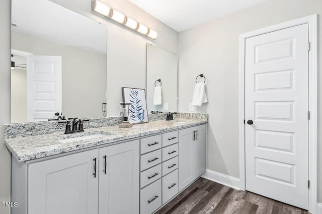 bathroom featuring double vanity, a sink, baseboards, and wood finished floors