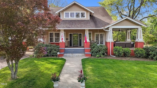craftsman-style house featuring ceiling fan, a shingled roof, covered porch, and a front yard