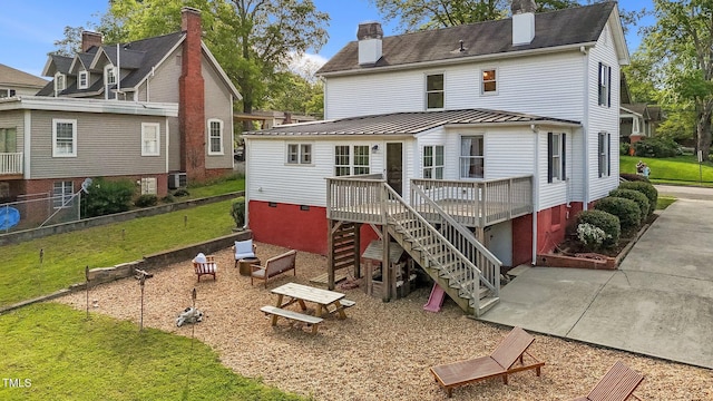 back of property with stairway, a deck, a patio, metal roof, and a standing seam roof