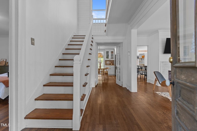 stairway featuring baseboards, wood finished floors, and crown molding