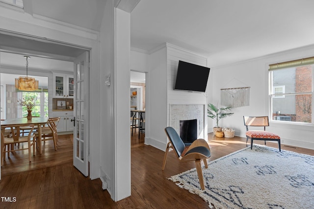 living area with a fireplace, crown molding, baseboards, and dark wood-style flooring