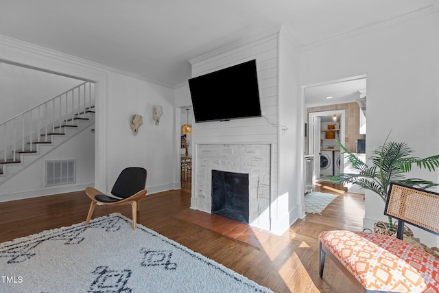 living room featuring washing machine and dryer, wood finished floors, visible vents, and stairway