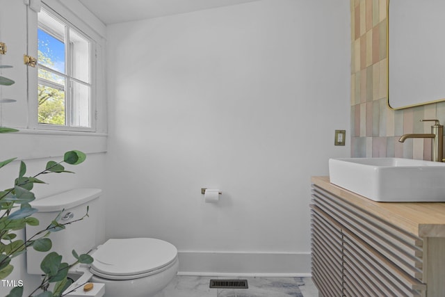 half bath with marble finish floor, visible vents, toilet, vanity, and baseboards