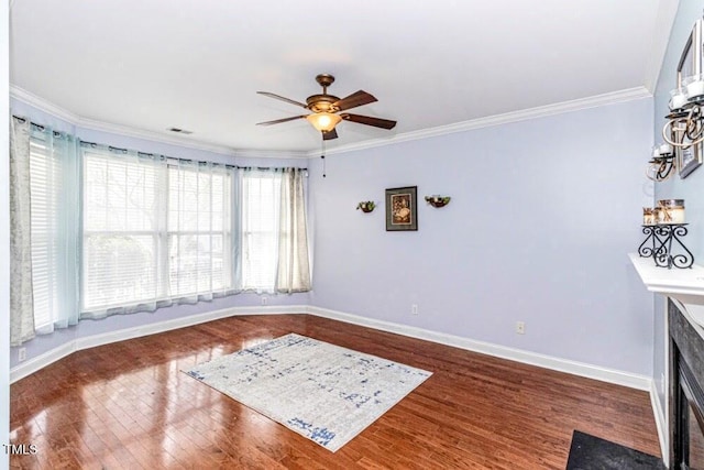 unfurnished room with ornamental molding, a ceiling fan, visible vents, wood finished floors, and baseboards