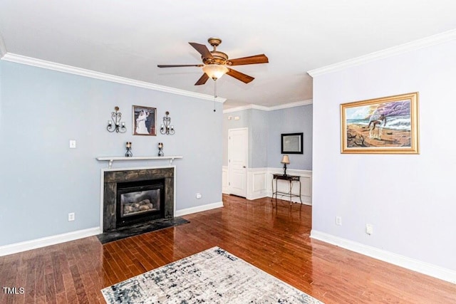 unfurnished living room featuring baseboards, ornamental molding, a ceiling fan, a fireplace, and wood finished floors
