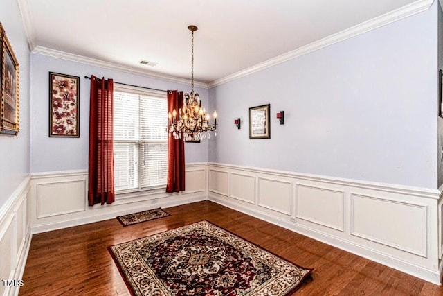 dining area with an inviting chandelier, crown molding, a wainscoted wall, visible vents, and dark wood finished floors