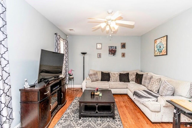 living area featuring wood finished floors, baseboards, a ceiling fan, and visible vents