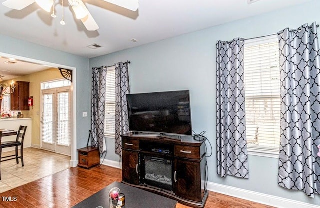 living area with a healthy amount of sunlight, visible vents, a ceiling fan, and wood finished floors