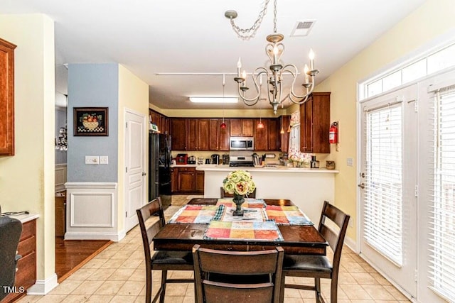 dining room with a decorative wall, visible vents, a chandelier, light tile patterned flooring, and wainscoting