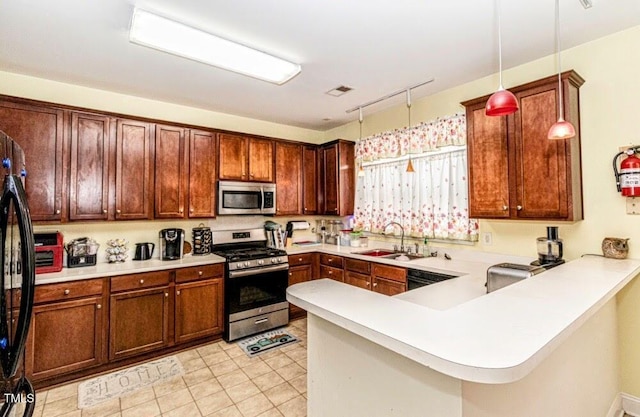 kitchen with a peninsula, light countertops, black appliances, pendant lighting, and a sink
