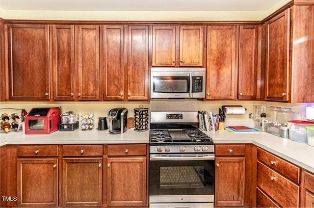 kitchen with brown cabinets, appliances with stainless steel finishes, and light countertops