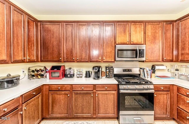 kitchen featuring brown cabinetry, appliances with stainless steel finishes, and light countertops