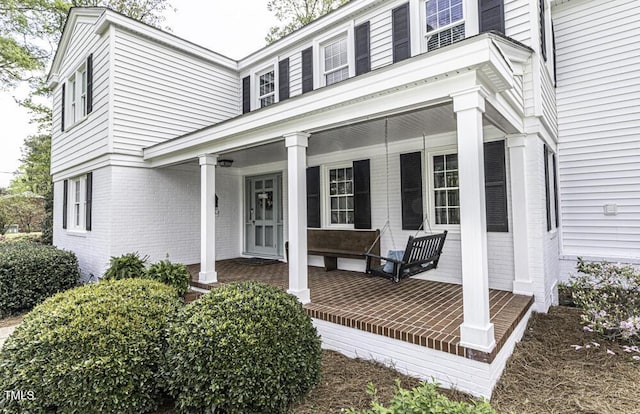 property entrance featuring brick siding and covered porch