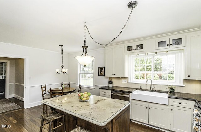 kitchen featuring a sink, a breakfast bar, a chandelier, crown molding, and dark wood-type flooring