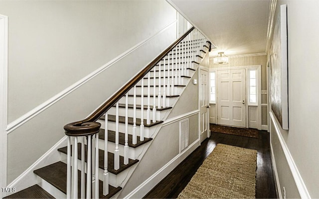 staircase featuring a chandelier, ornamental molding, and wood finished floors