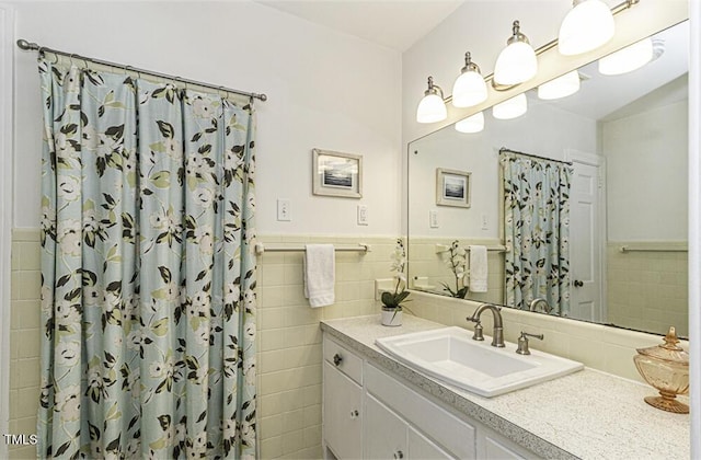 bathroom featuring vanity, tile walls, a shower with curtain, and a wainscoted wall