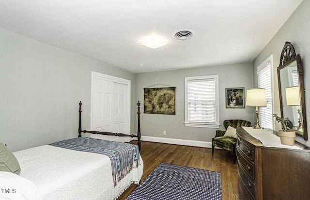 bedroom featuring a closet, baseboards, dark wood finished floors, and visible vents