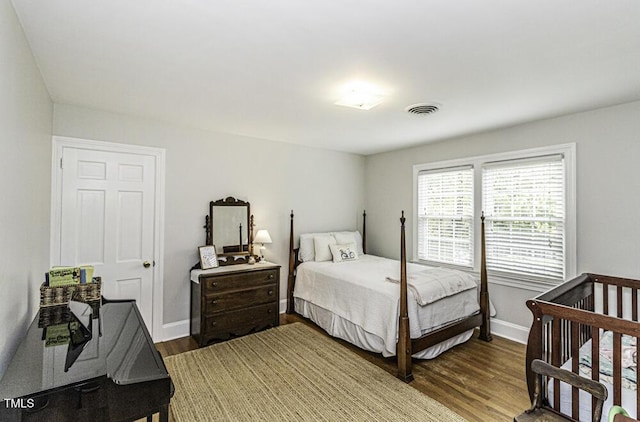 bedroom with visible vents, baseboards, and wood finished floors