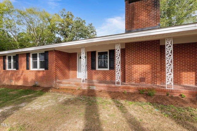 doorway to property with brick siding and a chimney