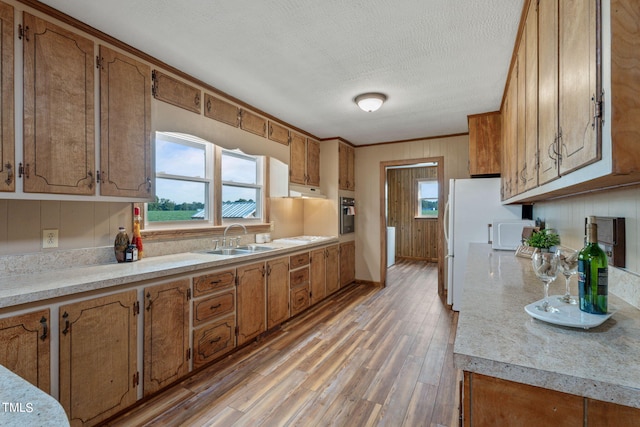 kitchen with brown cabinetry, a sink, and light wood-type flooring