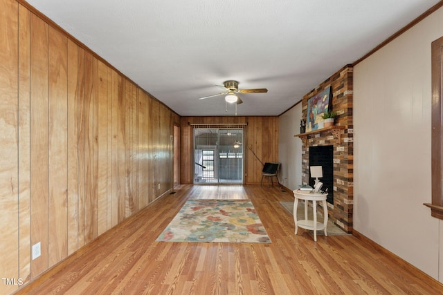 unfurnished living room featuring wooden walls, a fireplace, a ceiling fan, and wood finished floors