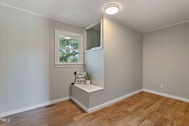interior space featuring baseboards, ornamental molding, wood finished floors, and visible vents