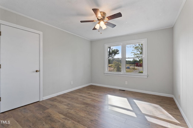 spare room with crown molding, ceiling fan, baseboards, and wood finished floors