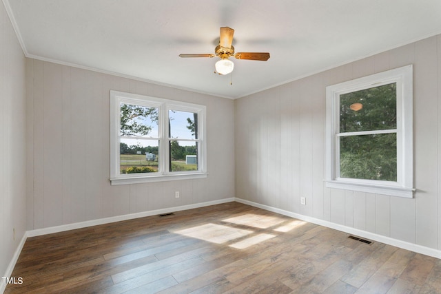 empty room with crown molding, ceiling fan, visible vents, and hardwood / wood-style flooring