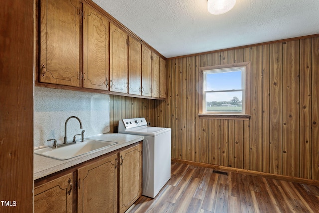 laundry area featuring cabinet space, a sink, a textured ceiling, washer / dryer, and light wood-type flooring