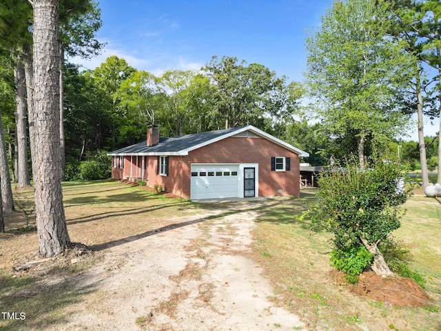 view of side of home with a chimney, brick siding, dirt driveway, an attached garage, and a yard