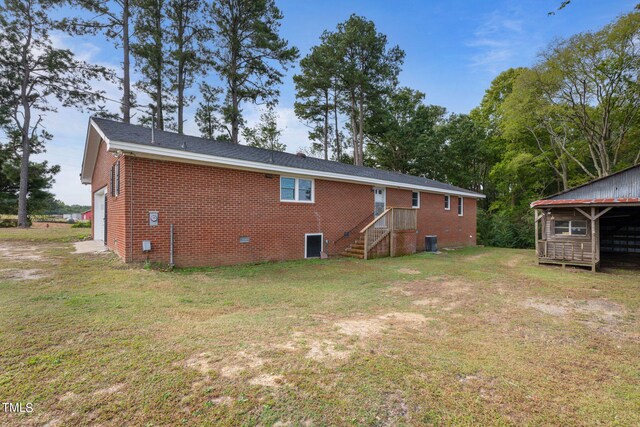back of house with brick siding, a garage, and a lawn