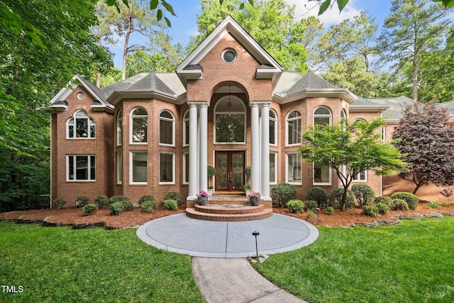 view of front of property featuring a front lawn, a shingled roof, french doors, and brick siding