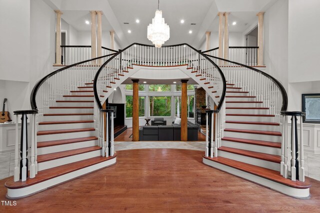 foyer entrance with recessed lighting, stairs, ornate columns, a notable chandelier, and a towering ceiling