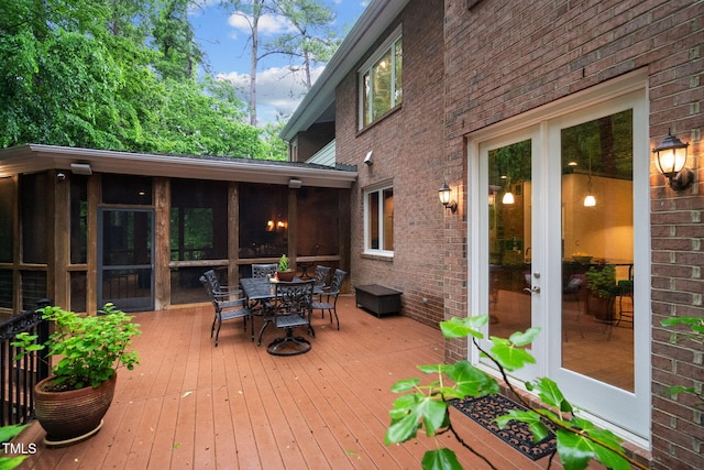 deck with outdoor dining space and a sunroom